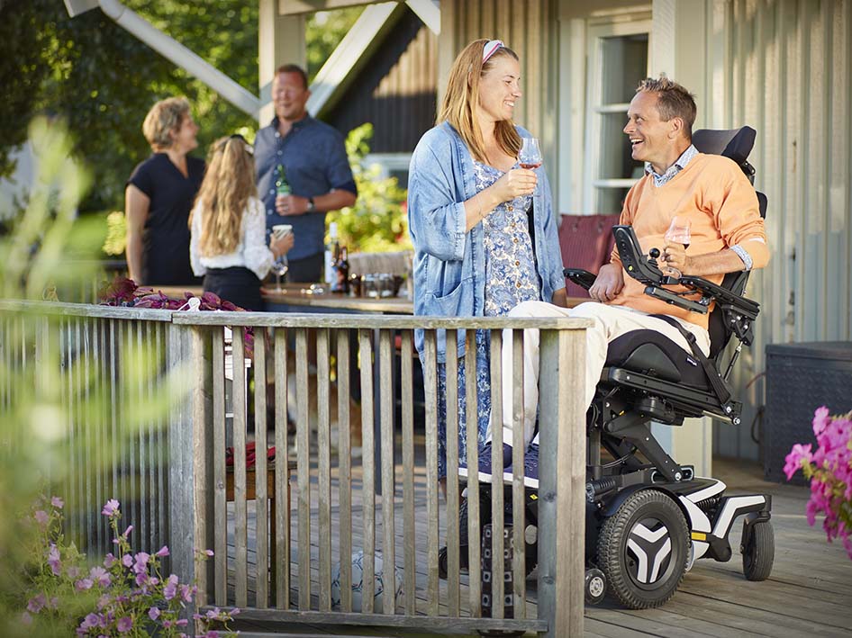 Man in Permobil F5 Corpus having drinks with family and friends. 