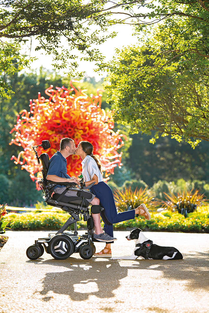 Permobil M5 Corpus powerchair with Active Reach - Man kissing girl in park - Beyond Mobility 